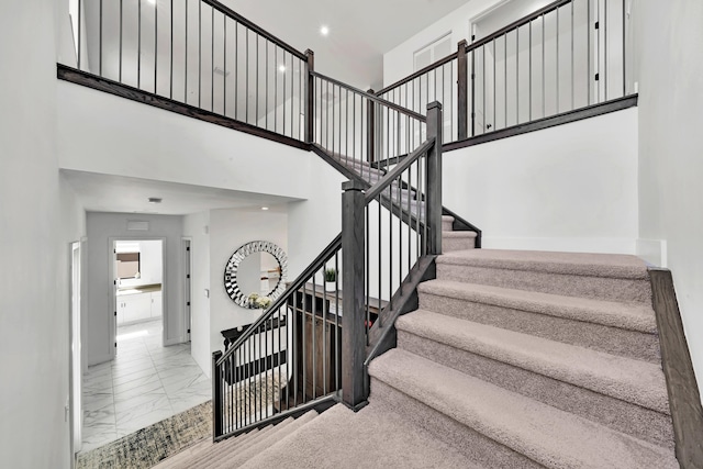 stairway featuring a towering ceiling