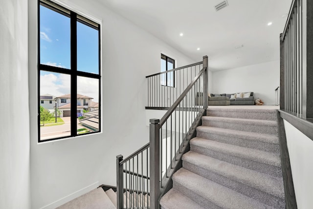 staircase with a wealth of natural light and carpet floors