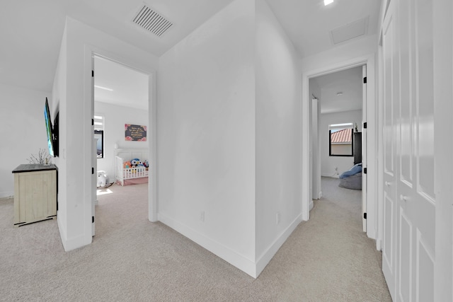 hallway with vaulted ceiling and light colored carpet