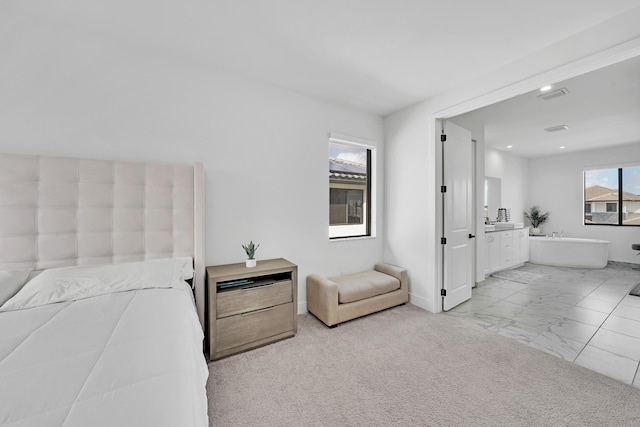 bedroom featuring ensuite bathroom and light carpet