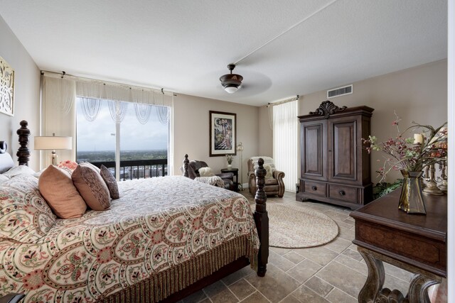 bedroom with access to exterior, ceiling fan, and a water view