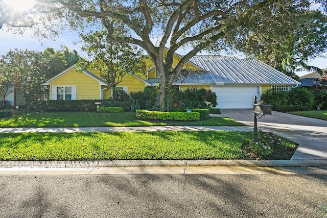 2388 Palm Harbor Dr, Palm Beach Gardens, FL 33410 - view of front of property with a front yard, driveway, an attached garage, and metal roof