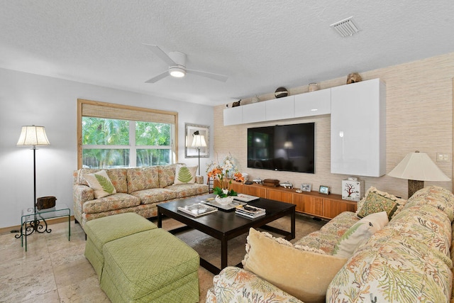 living room featuring ceiling fan and a textured ceiling