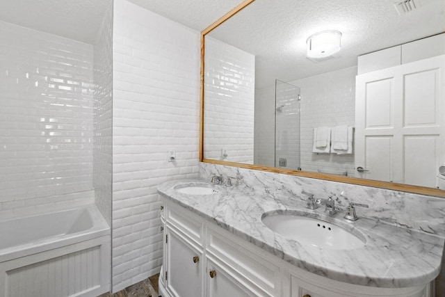 bathroom with vanity, a textured ceiling, hardwood / wood-style flooring, and plus walk in shower