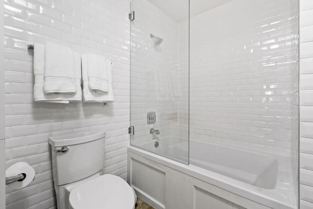 bathroom featuring toilet and combined bath / shower with glass door