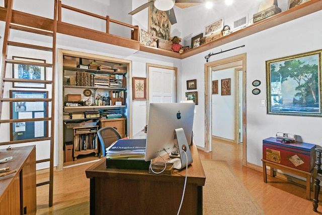 home office with light hardwood / wood-style floors and ceiling fan