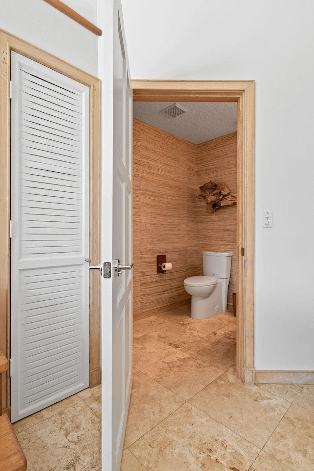 bathroom with toilet and wood walls