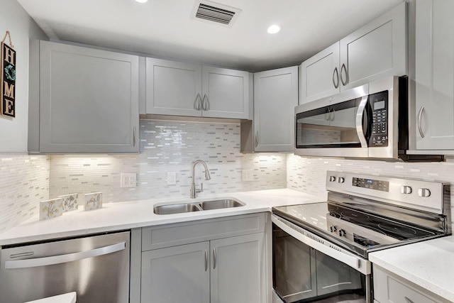 kitchen featuring sink, gray cabinets, backsplash, and stainless steel appliances