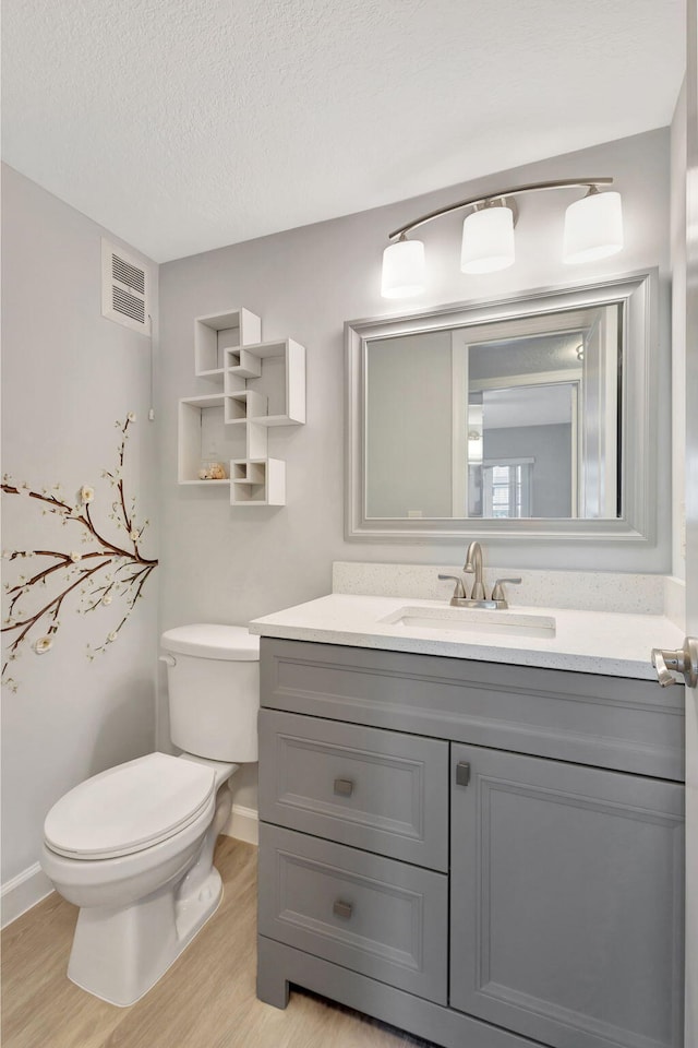 bathroom with vanity, toilet, hardwood / wood-style floors, and a textured ceiling