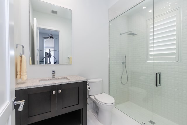 bathroom featuring toilet, a shower with shower door, and vanity