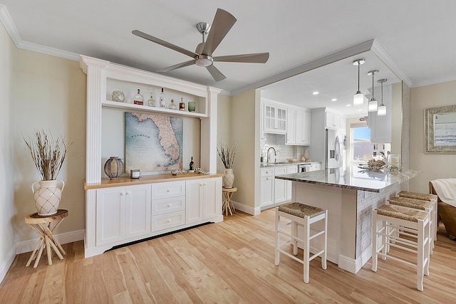 kitchen with white cabinets, hanging light fixtures, light hardwood / wood-style flooring, butcher block counters, and stainless steel refrigerator with ice dispenser