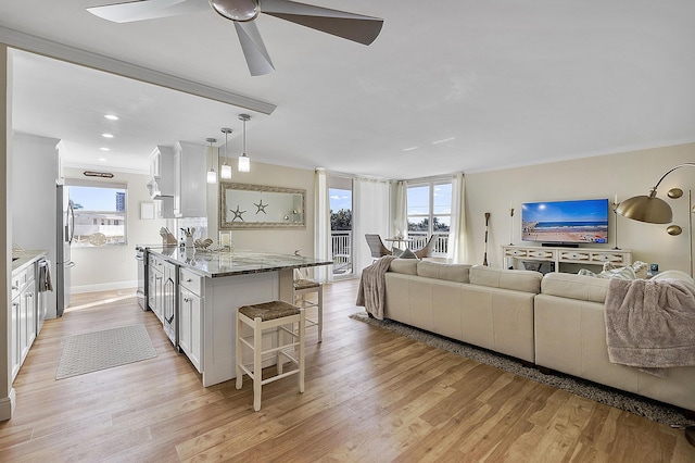 kitchen featuring a kitchen bar, ornamental molding, open floor plan, and appliances with stainless steel finishes