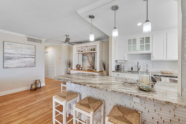 kitchen with ceiling fan, white cabinetry, light hardwood / wood-style floors, decorative light fixtures, and light stone counters