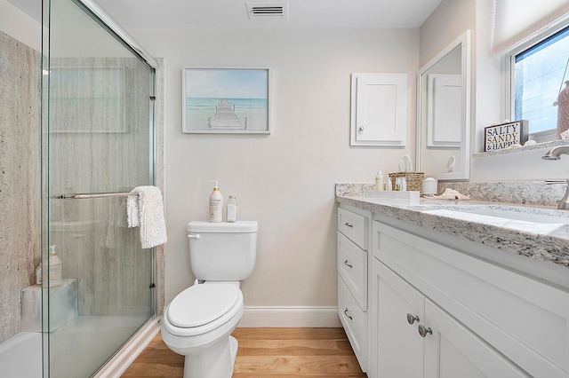 bathroom featuring vanity, wood-type flooring, toilet, and an enclosed shower