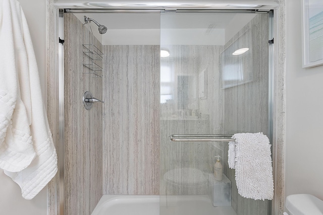 bathroom with toilet and a shower with door