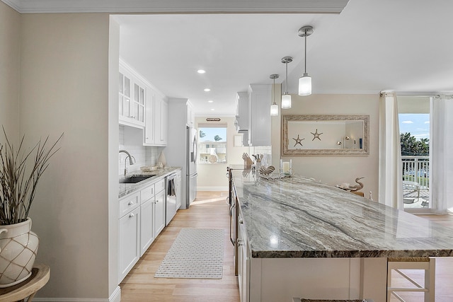 kitchen with decorative backsplash, hanging light fixtures, white cabinetry, stainless steel appliances, and sink