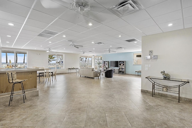 living area featuring a paneled ceiling, a ceiling fan, visible vents, and light tile patterned floors