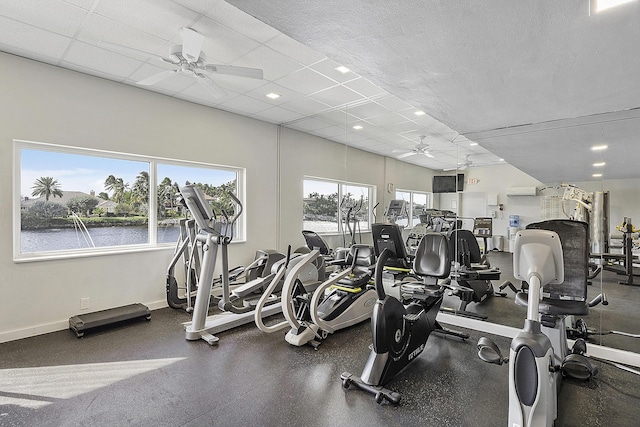 workout area featuring baseboards, a ceiling fan, and a water view