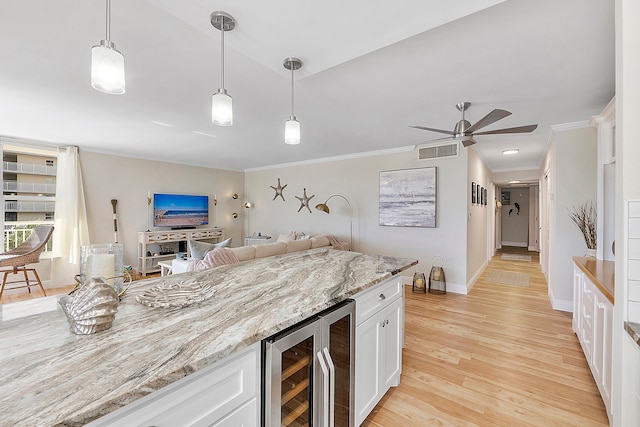 kitchen featuring beverage cooler, light stone counters, white cabinetry, light hardwood / wood-style floors, and decorative light fixtures