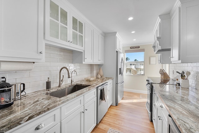 kitchen with white cabinets, appliances with stainless steel finishes, light hardwood / wood-style flooring, ornamental molding, and sink