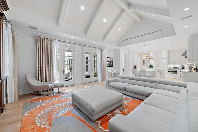 living room with french doors, beam ceiling, sink, light wood-type flooring, and high vaulted ceiling