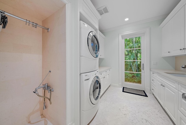 laundry room with cabinets, stacked washing maching and dryer, sink, and ornamental molding