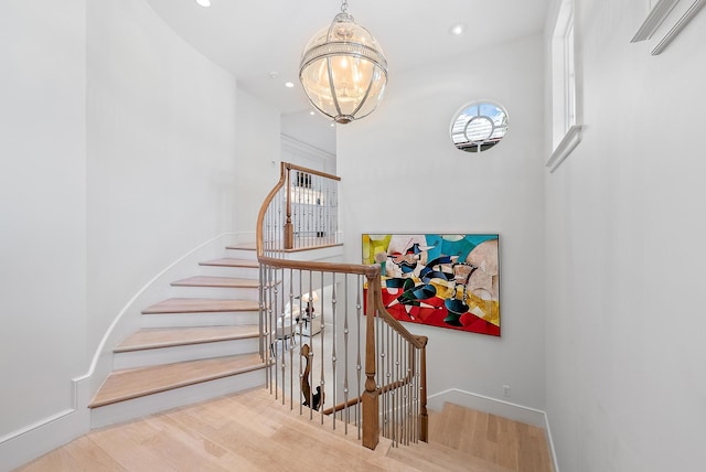 staircase featuring an inviting chandelier and hardwood / wood-style floors