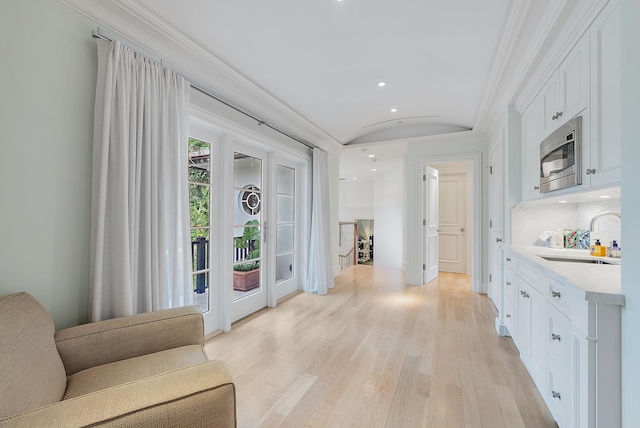 hallway featuring light hardwood / wood-style flooring, ornamental molding, and sink