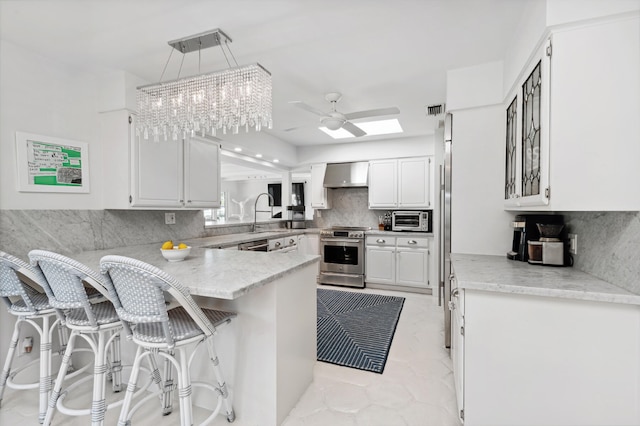 kitchen with a breakfast bar area, kitchen peninsula, decorative light fixtures, stainless steel range with electric cooktop, and white cabinets