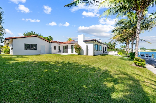 back of house with a water view and a lawn