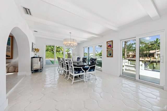 dining room featuring beamed ceiling, a chandelier, and a water view