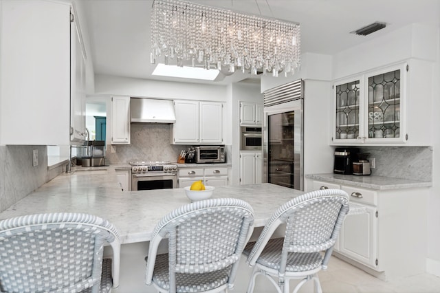 kitchen with white cabinetry, kitchen peninsula, wall chimney exhaust hood, and high end appliances