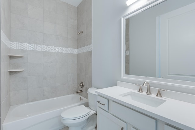 full bathroom featuring vanity, tiled shower / bath combo, and toilet