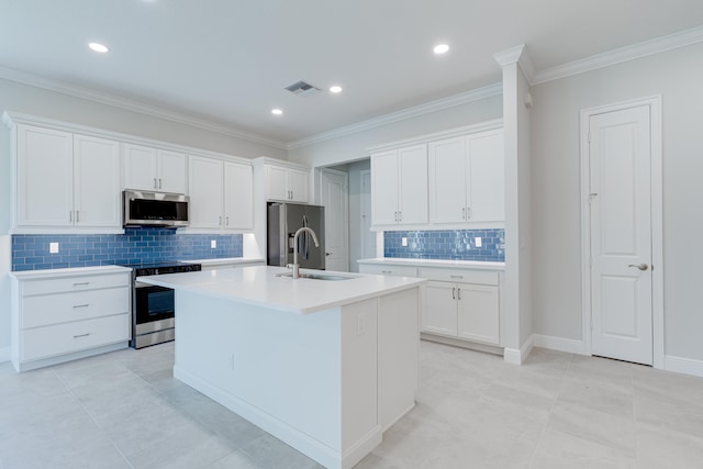 kitchen with a kitchen island with sink, stainless steel appliances, sink, light tile patterned flooring, and white cabinets