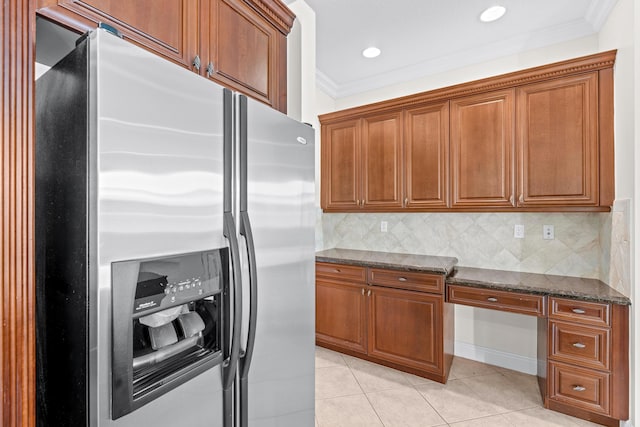 kitchen featuring backsplash, crown molding, light tile patterned floors, dark stone countertops, and stainless steel fridge with ice dispenser