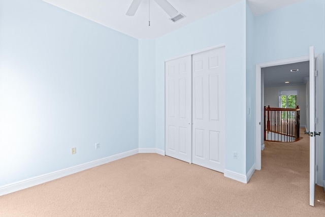 unfurnished bedroom featuring light carpet, a closet, and ceiling fan