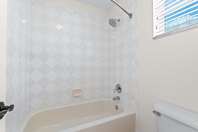 bathroom with toilet and tiled shower / bath