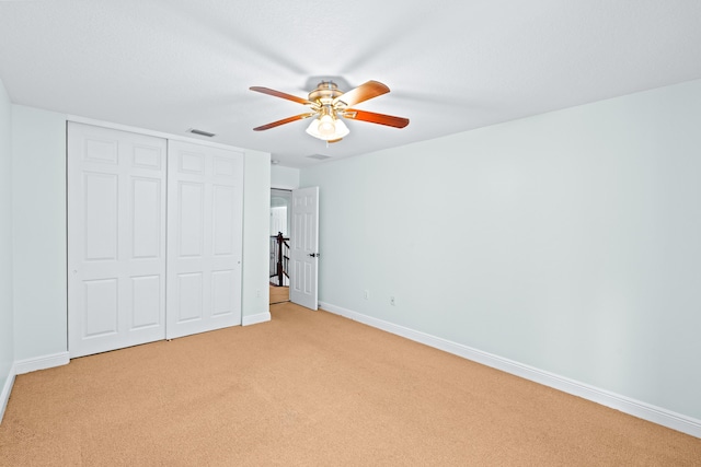 unfurnished bedroom with ceiling fan, a closet, and light colored carpet