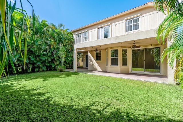 rear view of property featuring a lawn, ceiling fan, and a patio