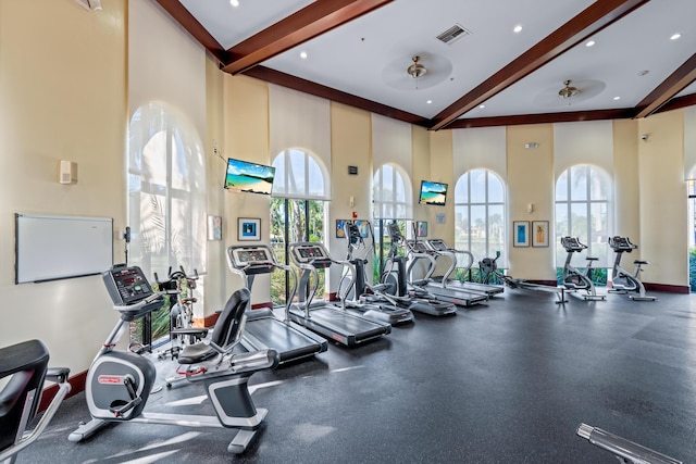 exercise room with ceiling fan and a high ceiling