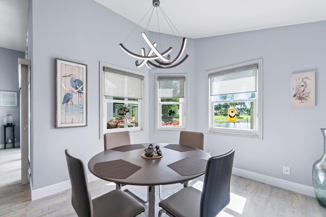 dining space with vaulted ceiling, a notable chandelier, and light hardwood / wood-style floors