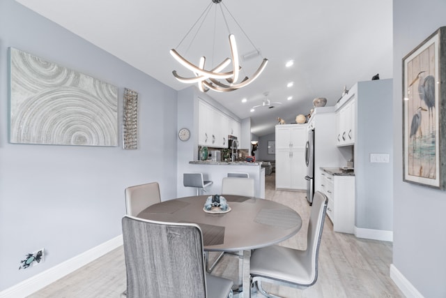 dining room featuring an inviting chandelier, vaulted ceiling, and light hardwood / wood-style flooring