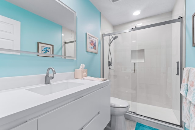 bathroom with toilet, vanity, and a shower with shower door