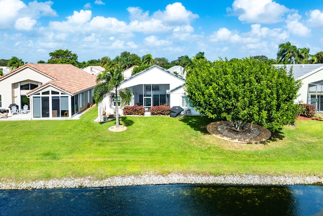 ranch-style home with a water view, a front lawn, and a sunroom