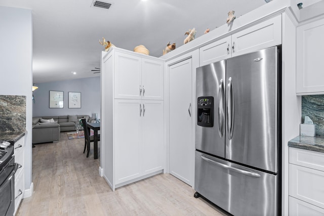 kitchen featuring dark stone countertops, white cabinets, vaulted ceiling, and stainless steel appliances