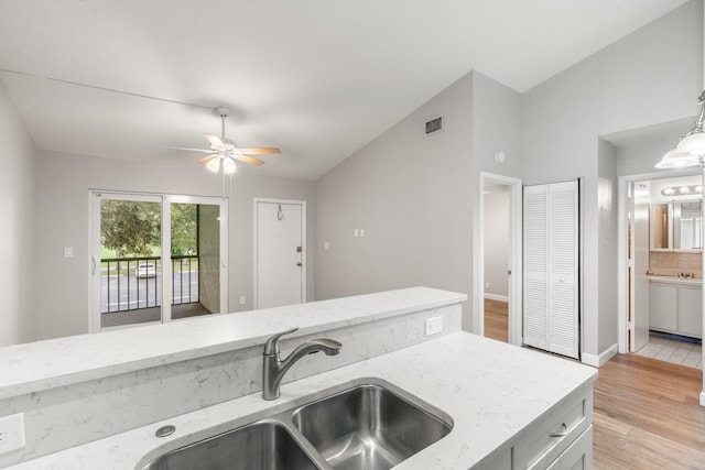 kitchen featuring ceiling fan, light wood-type flooring, vaulted ceiling, pendant lighting, and sink