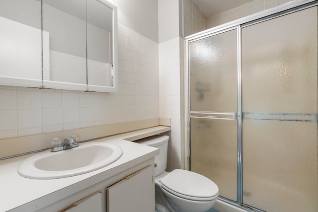 bathroom featuring vanity, tile walls, a shower with door, and toilet