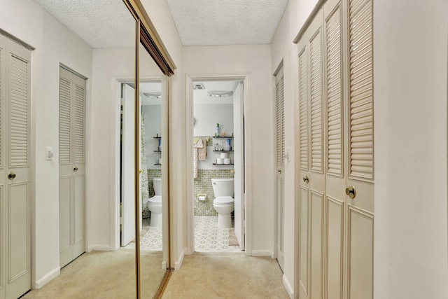 hallway featuring light colored carpet and a textured ceiling