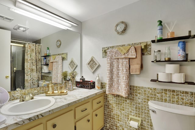 bathroom with vanity, toilet, and tile walls