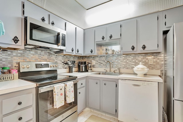 kitchen with backsplash, sink, light tile patterned floors, and appliances with stainless steel finishes